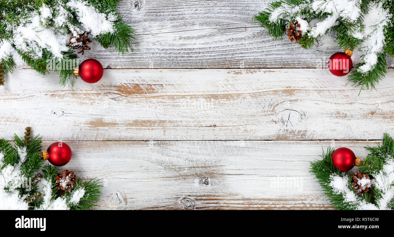 Christmas snow covered evergreen branches and red ball decorations in ...
