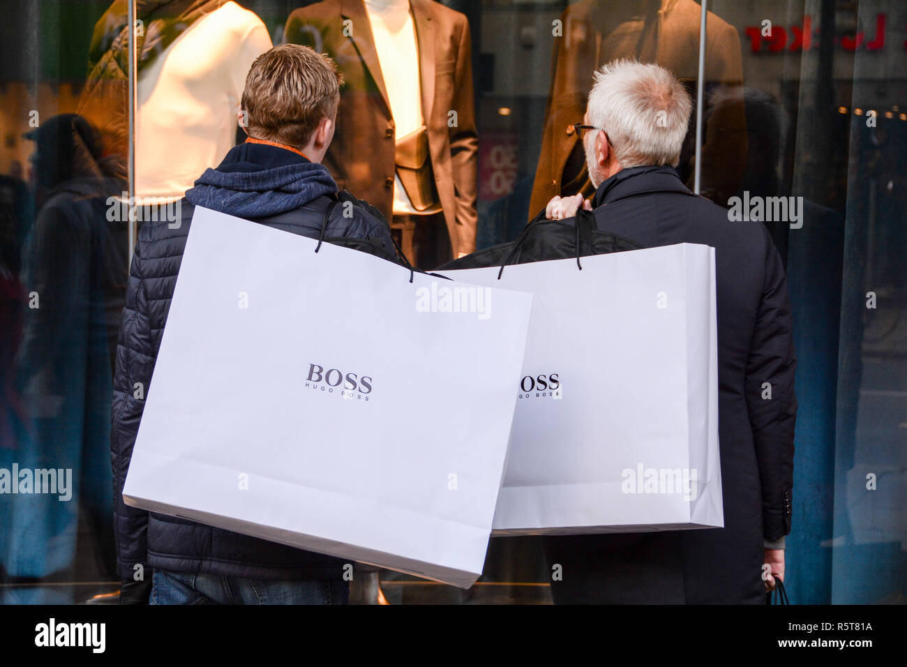 Two male shoppers on a busy Oxford Street carrying large Hugo Boss paper  carrier bags on their shoulders Stock Photo - Alamy