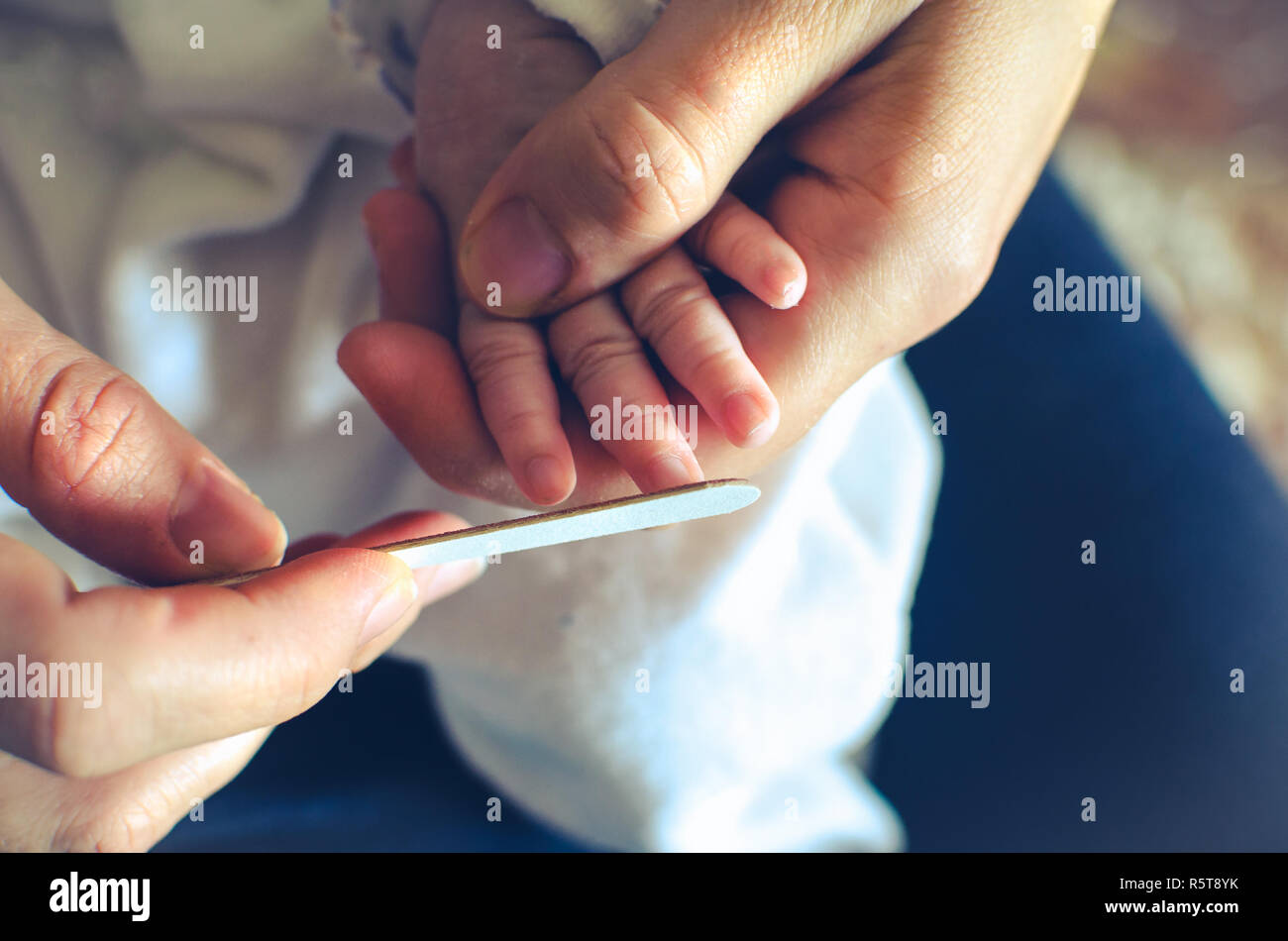 filing nails newborn avoid scratches - baby nail file cut Stock Photo