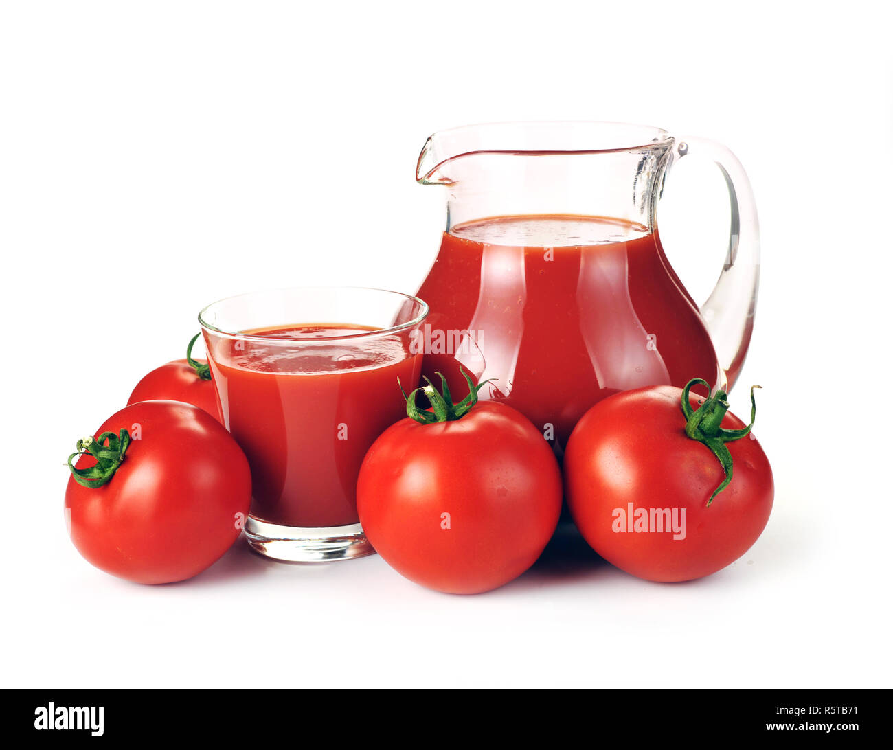 Jug, glass of tomato juice and fruits with green leaves on a white
