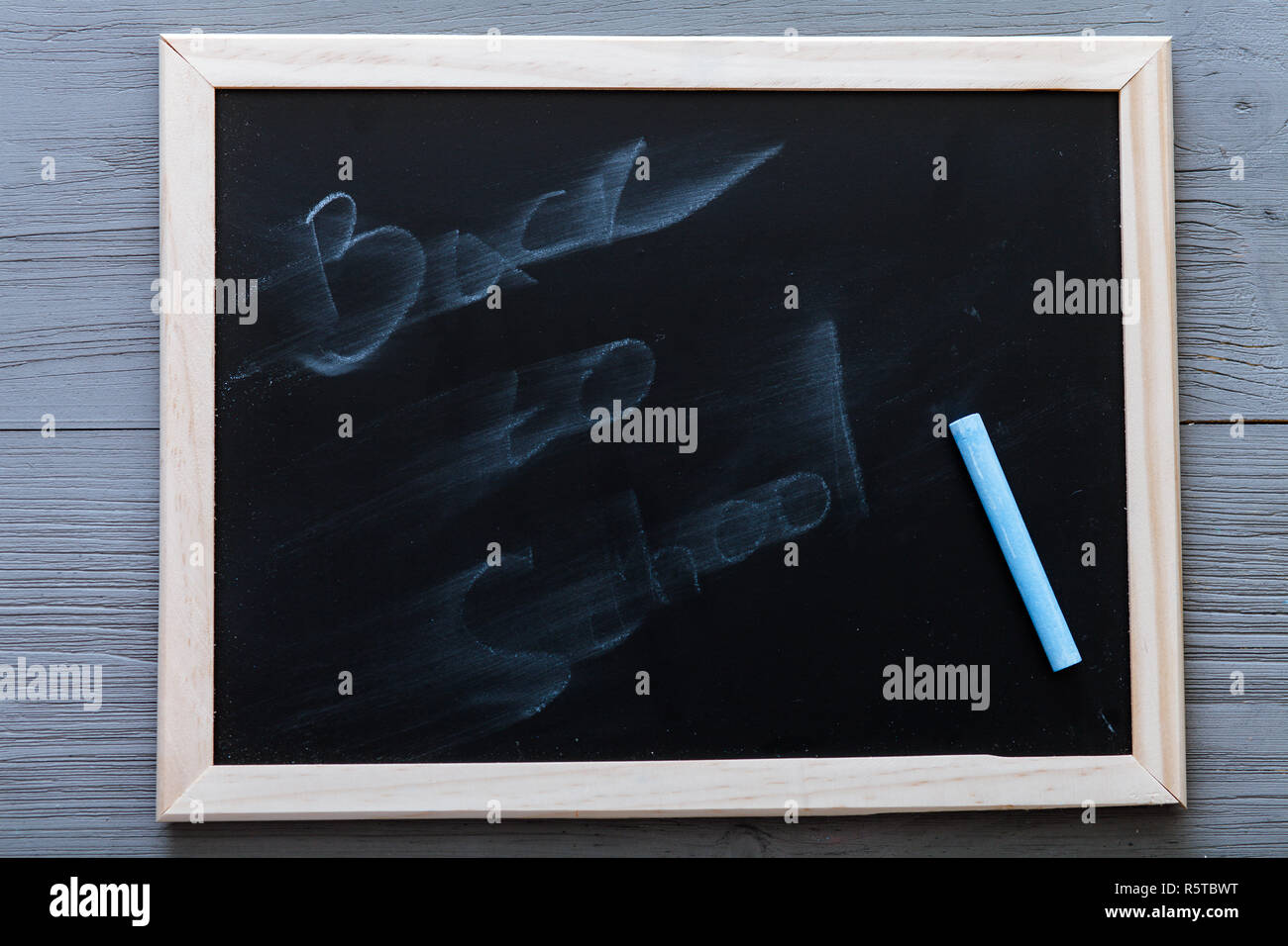 Black board with back to school erased by chalkboard eraser and chalk on grey wooden background, kids recess holidays concept, lesson break, year endi Stock Photo