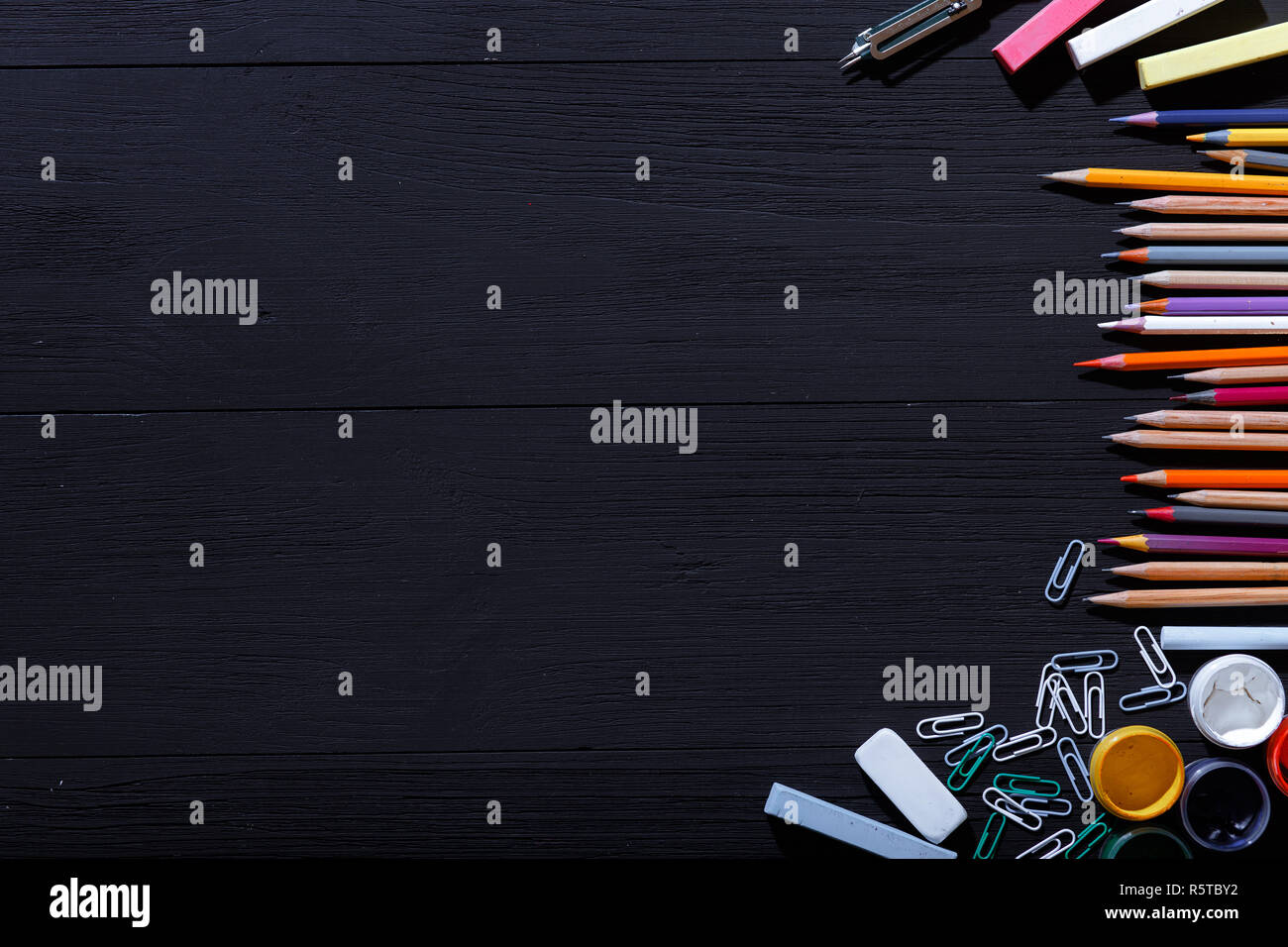 Back to school concept, colorful pencils on black art table, multicolored stationery supplies for teaching kids drawing on empty dark wooden desk, cre Stock Photo
