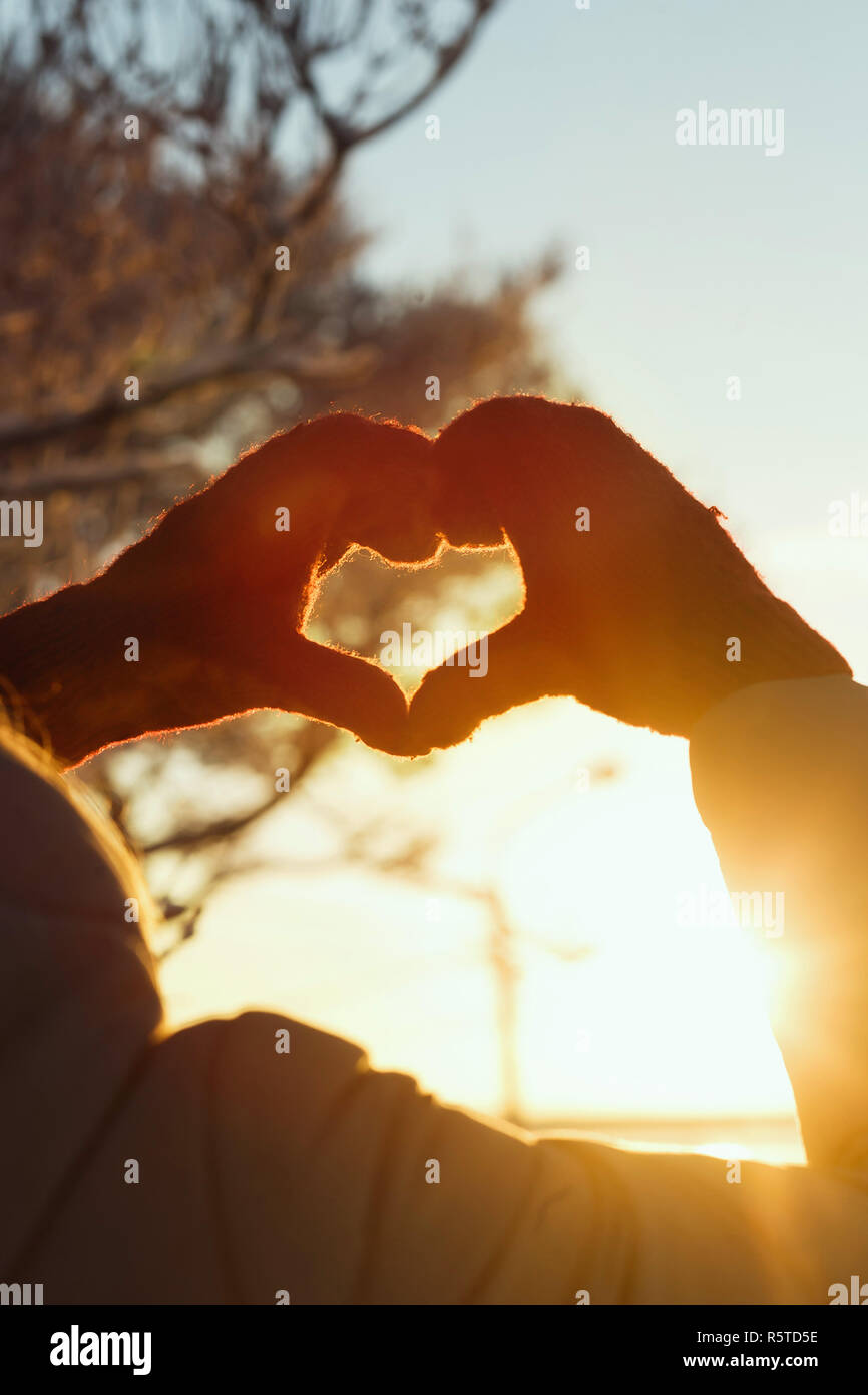Heart shape symbol of the women mittens in winter frosty sunset. Concept of winter, dating, valentines day and love. Stock Photo
