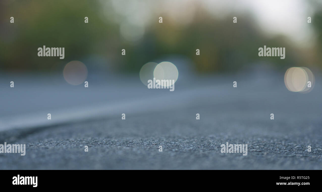 low angle shot of blurred moving cars on city street with closeup focus on sidewalk Stock Photo