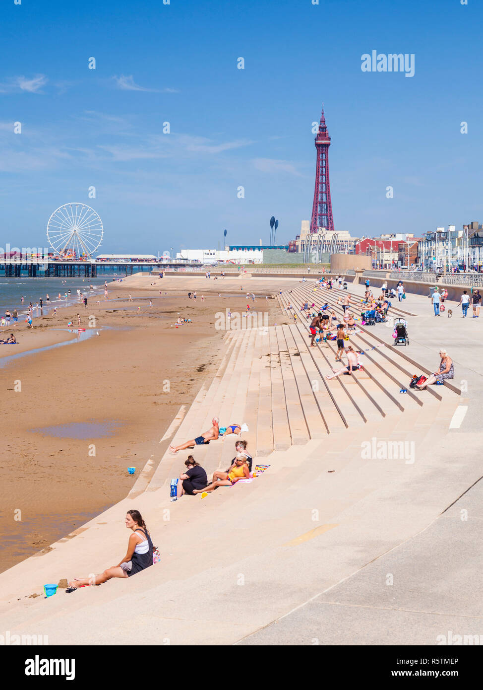 People on the sandy beach at Blackpool uk beach summer Blackpool tower central pier and new promenade Blackpool Lancashire England UK GB Europe Stock Photo