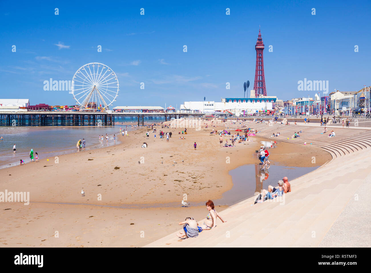 People on the sandy beach at Blackpool beach summer with Blackpool tower central pier and promenade Blackpool Lancashire England UK GB Europe Stock Photo