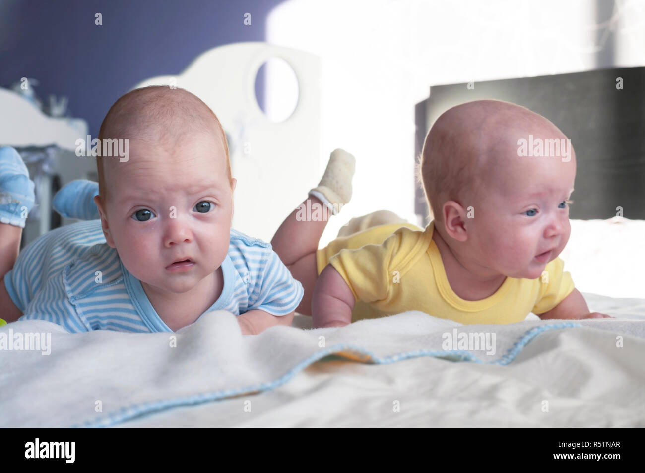 Cute Little Twins Babies Boy And Girl Are Lying On The Bed And Learning To Hold Their Heads Stock Photo Alamy