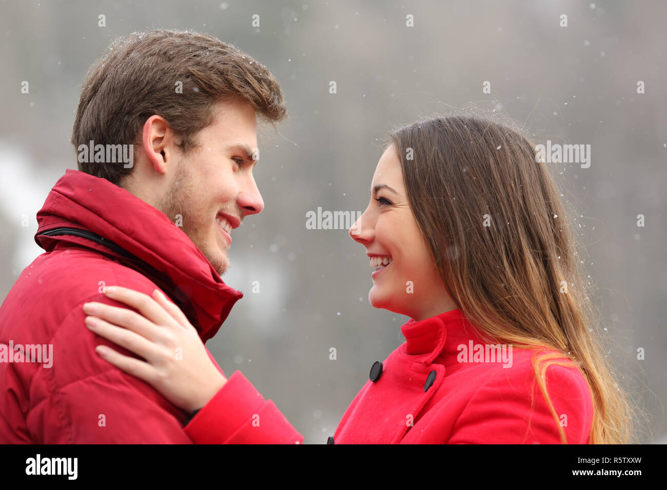 Side view portrait of a happy couple in love looking each other in winter Stock Photo
