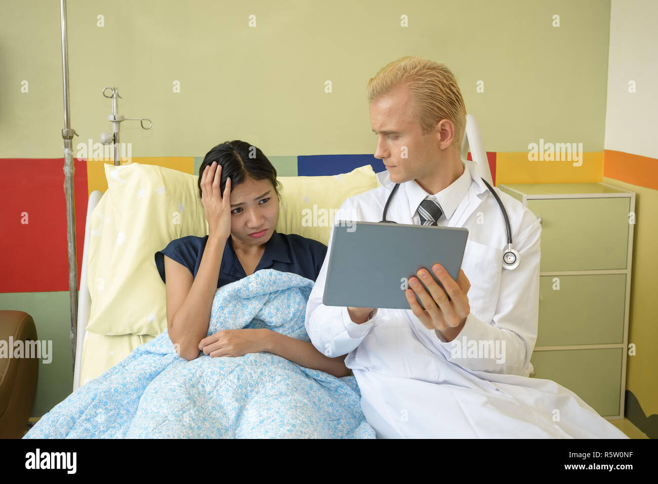 caucasian doctor with suffering patient, using digital tablet Stock Photo