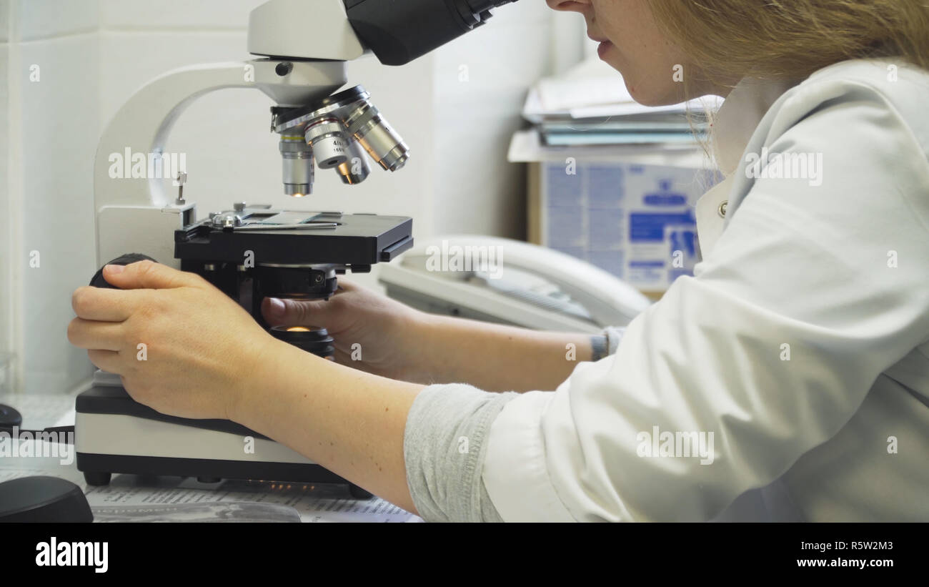 Doctor woman working with a microscope in Laboratory. Female scientist looking through a microscope in lab. Scientist using a microscope in a laboratory. Stock Photo
