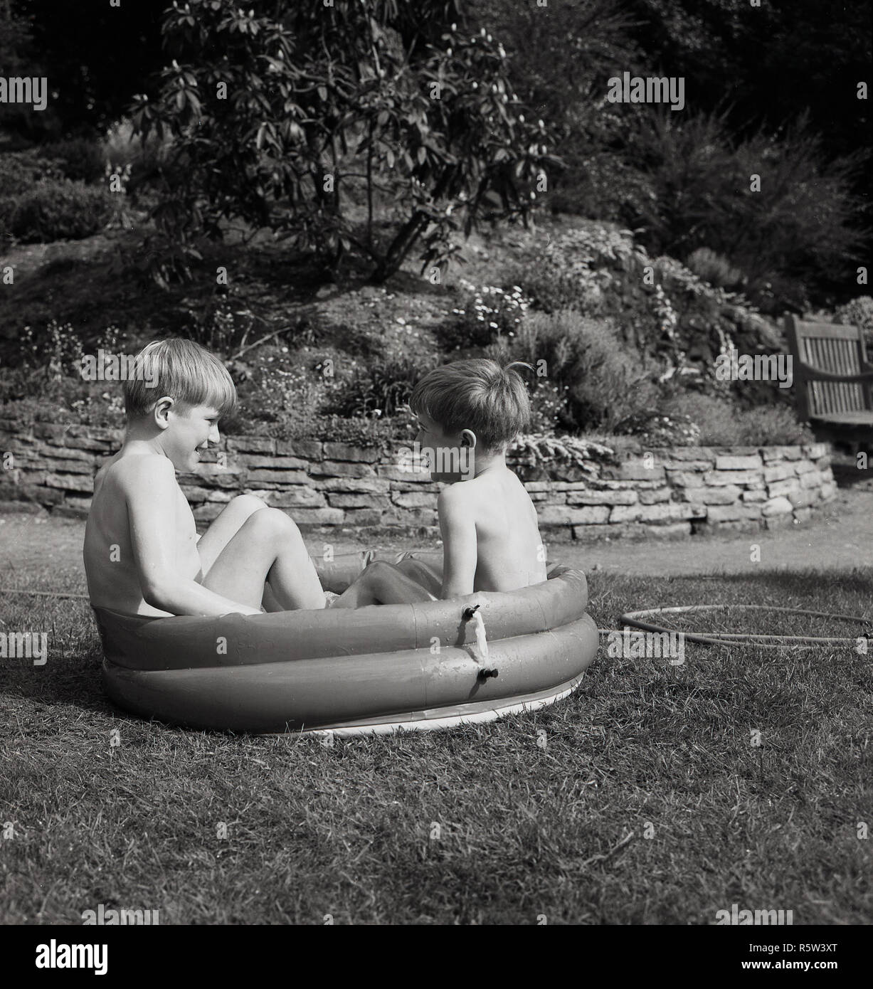 1960s, historical, outside in a garden, two little boys sitting in a small rubber paddling pool. Stock Photo