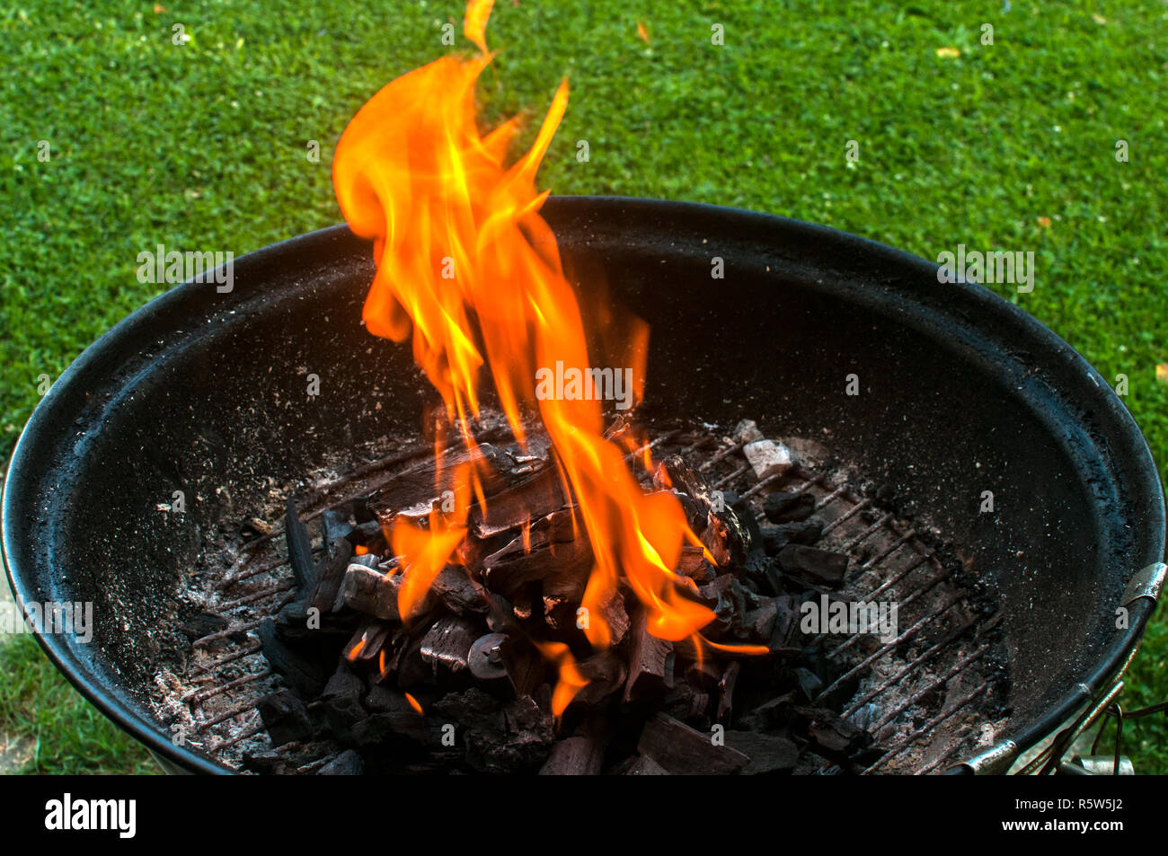 Charcoal barbecue grill with burning fire flame closeup on home garden