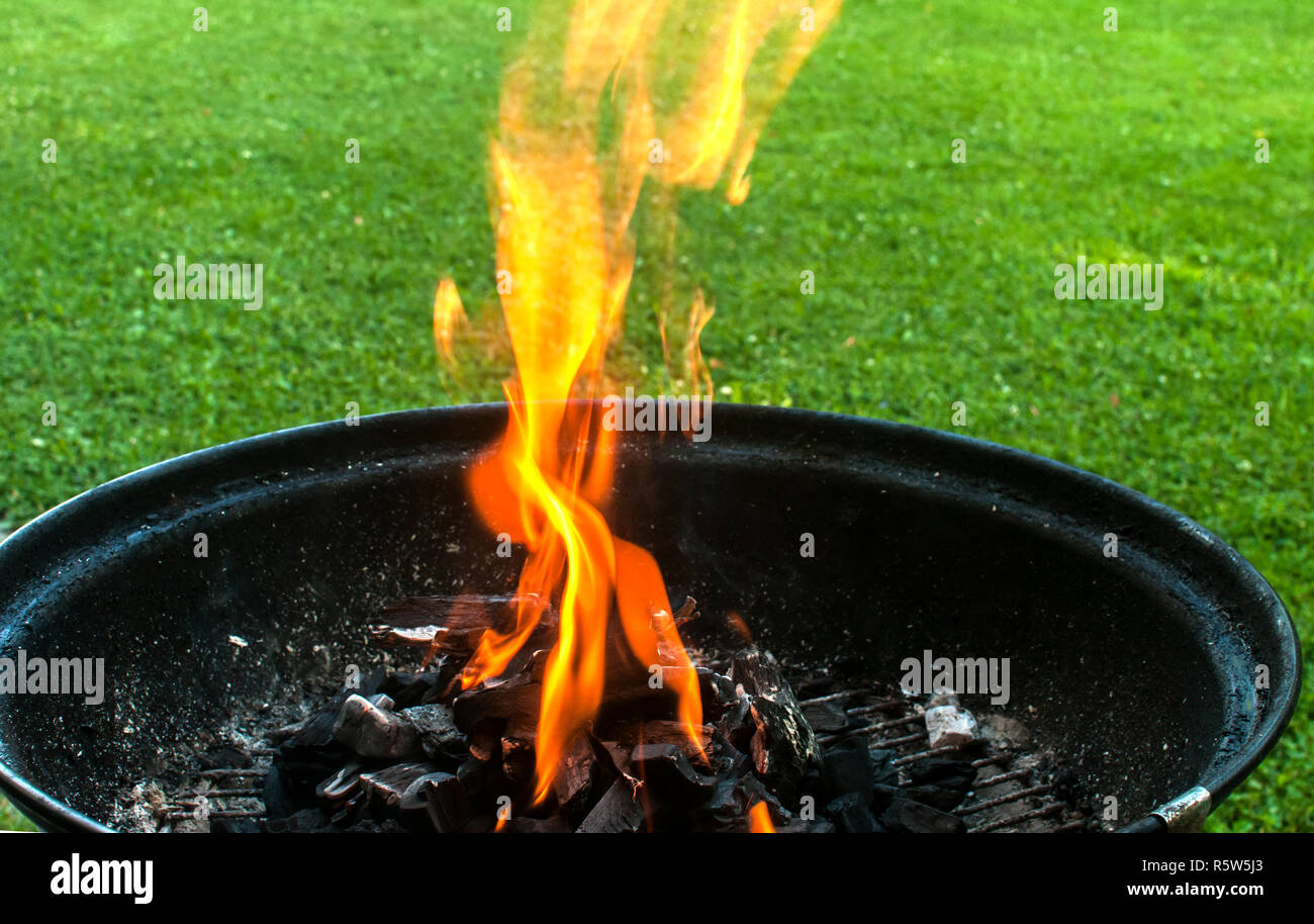 Charcoal barbecue grill with burning fire flame closeup on home garden