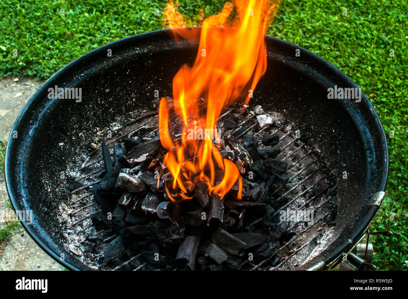Charcoal barbecue grill with burning fire flame closeup on home garden
