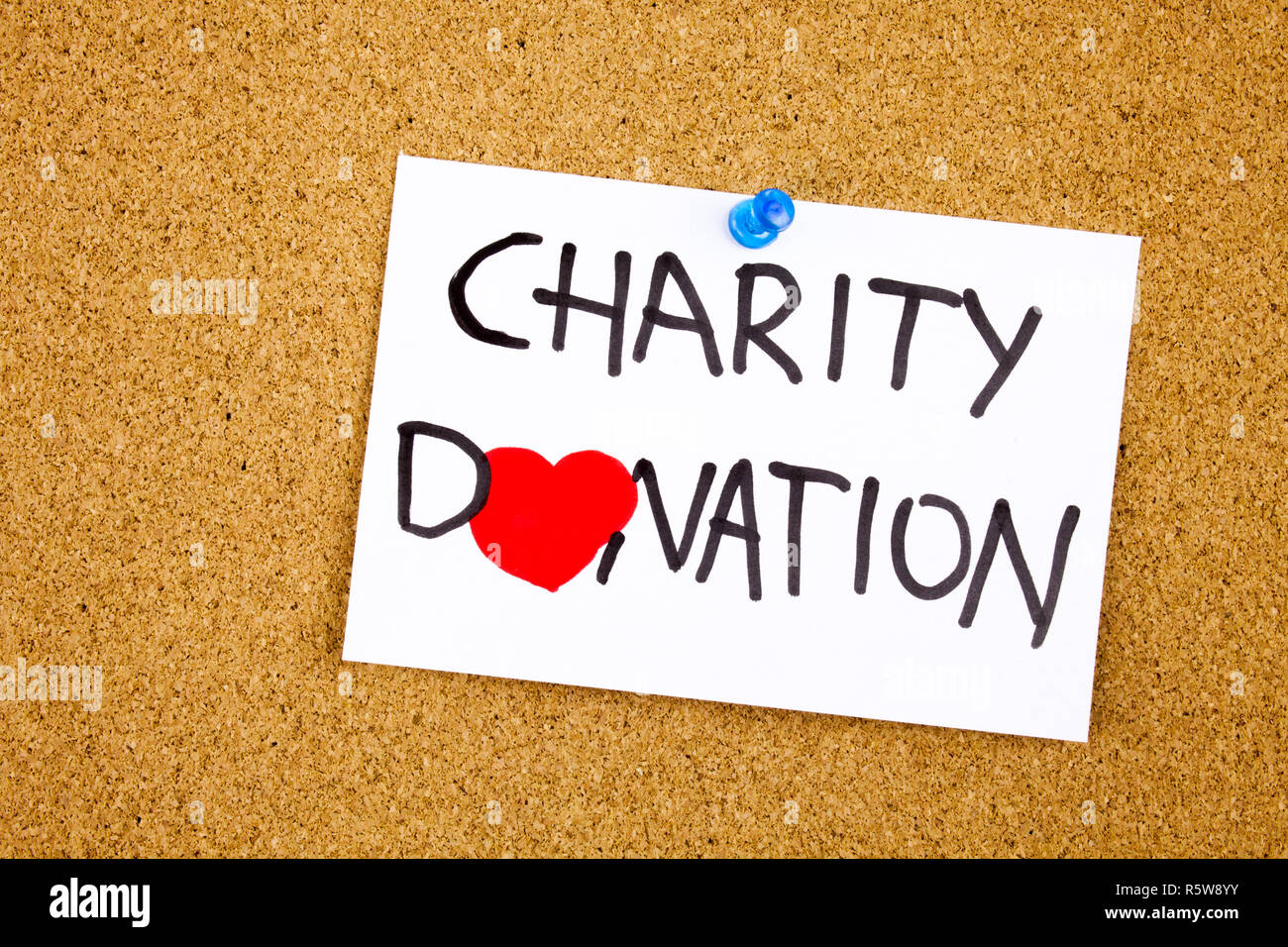charity donation phrase handwritten on sticky note pinned to a cork notice heart symbol instead of O Stock Photo