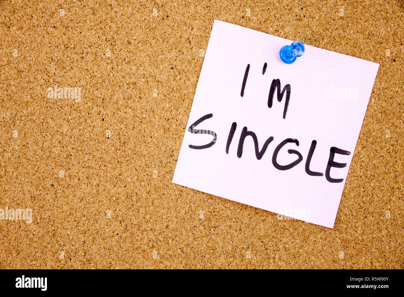 Torn note paper attached with blue pin to cork board, good as background or backdrop I am single Stock Photo