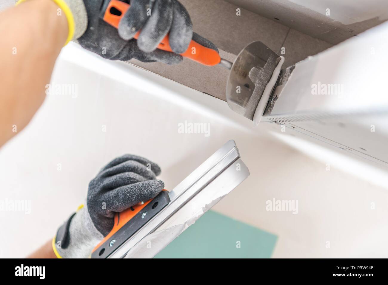 Drywall Ceiling Elements For LED Lighting Building. Worker Patching Drywall. Construction Theme. Stock Photo