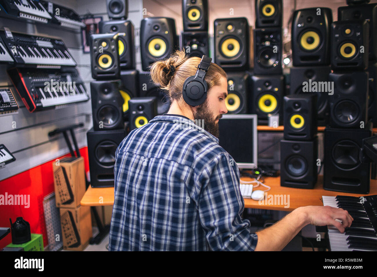 Serious and concentrated oyung man creating music in studio. He records  music by playing on keyboard. Hipster work at computer as well. Manu sound  spe Stock Photo - Alamy
