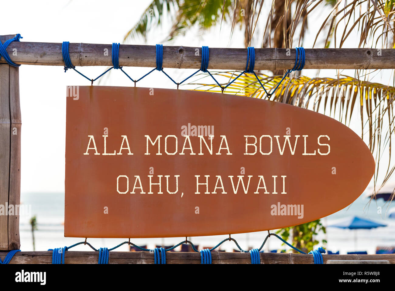 Orange vintage signboard in shape of surfboard with Ala Moana Bowls Oahu, Hawaii text for surf spot and palm tree in background Stock Photo