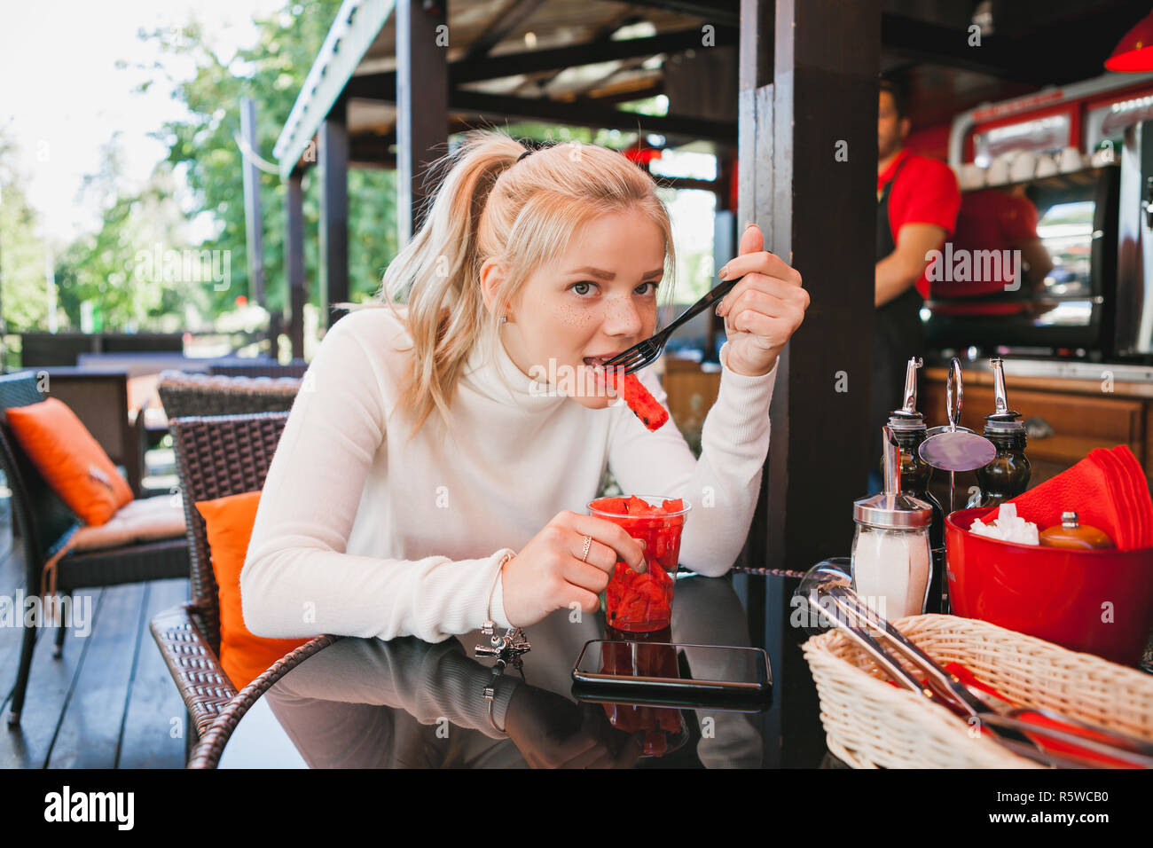 Young beautiful woman eating watermelon in the outdoor restaurant. Funny and beautiful Stock Photo