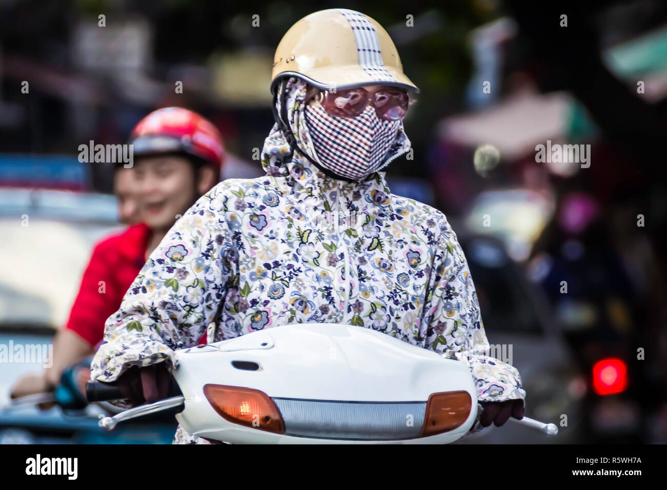 female in protective against air pollution mask and helmet. Car reflection in sunglasses. Stock Photo