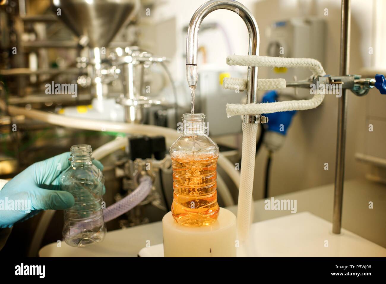 Lab technican carbonates an orange fizzy drink Stock Photo