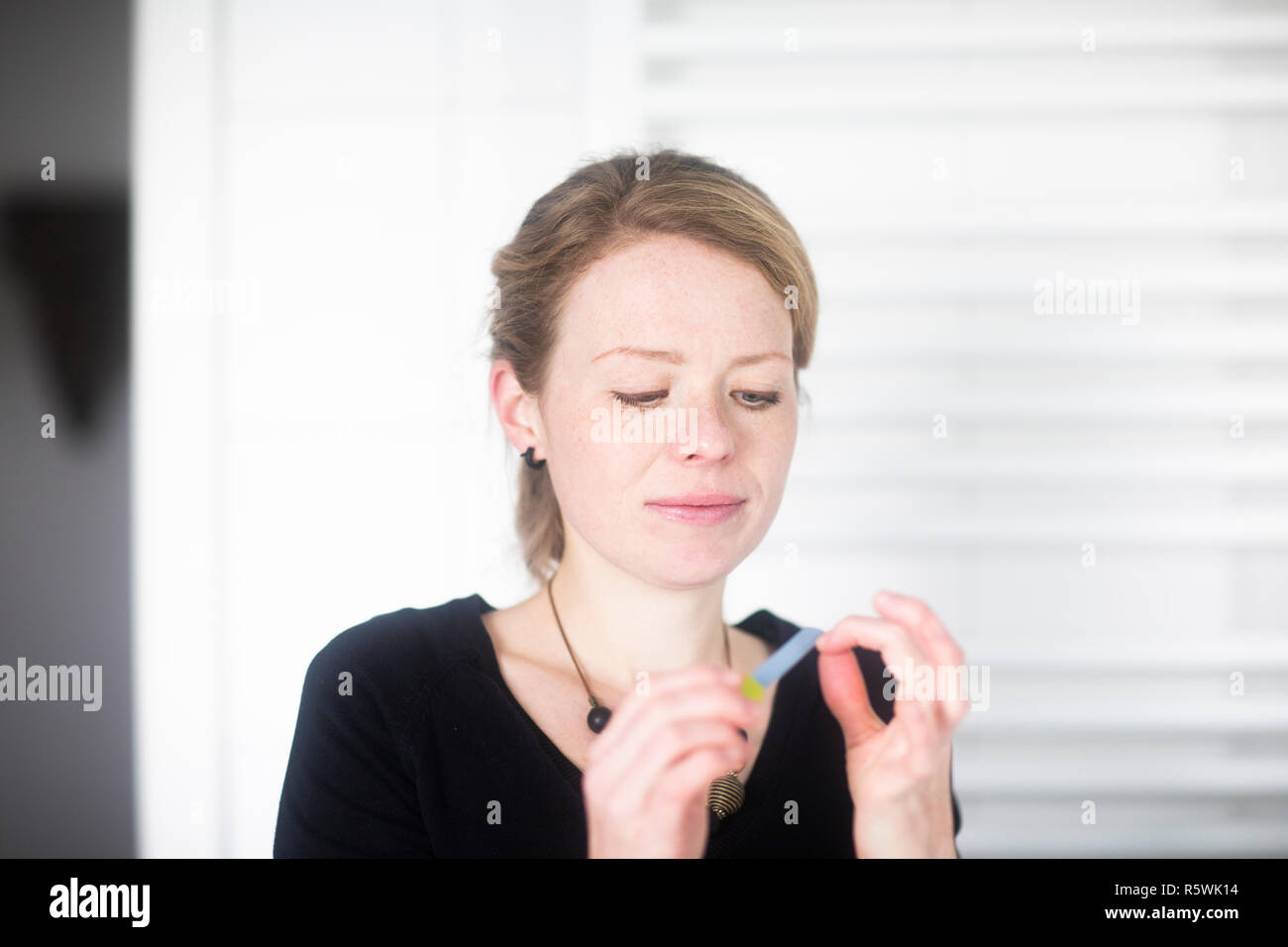 Portrait of a woman filing her nails in the bathroom Stock Photo