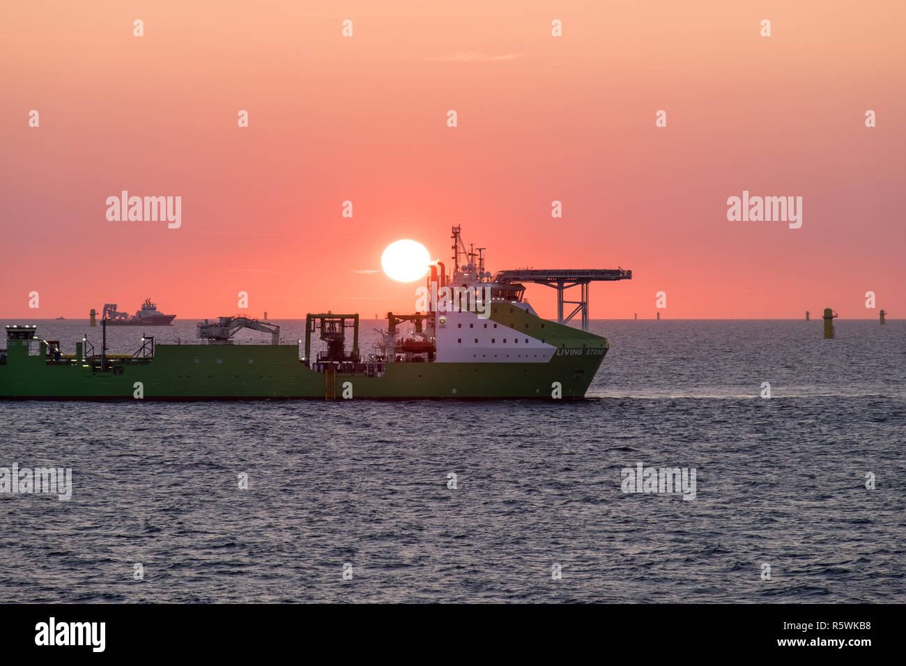 DEME Group's offshore construction support vessel, Living Stone, working at sunset on the Hornsea Project One Offshore Wind Farm, the North Sea, UK Stock Photo
