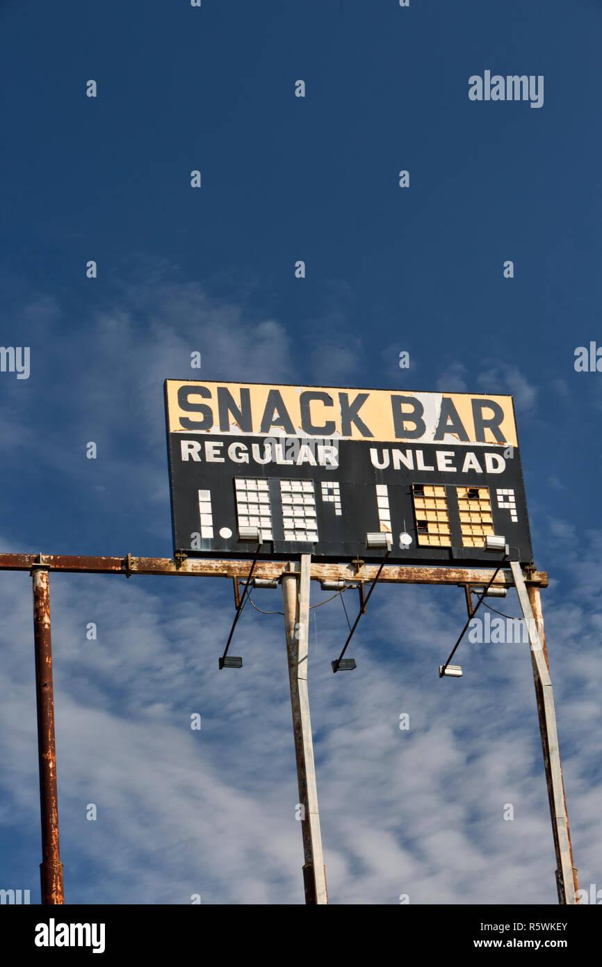 Elevated Vintage Gas Station Sign 'Snack Bar - Regular - Unlead' gasoline,  against a scattered blue sky. Stock Photo