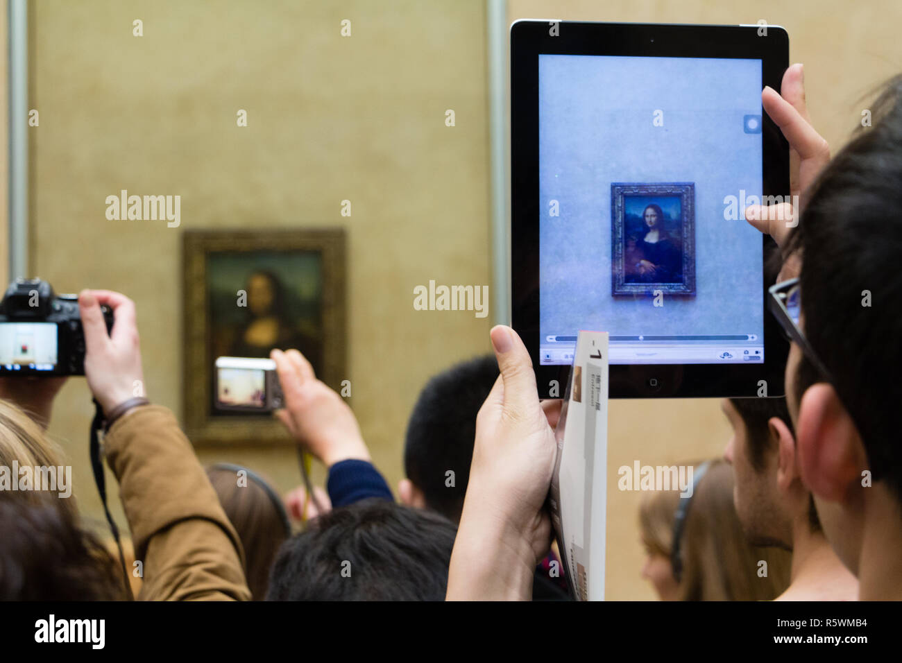 People taking pictures of the Mona Lisa portrait with their phones and ipads in the Louvre in Paris, France Stock Photo