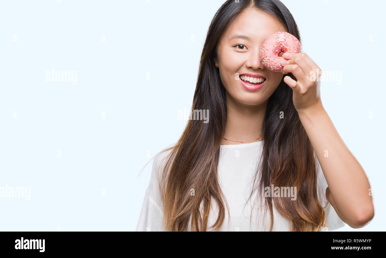 Young Asian Woman Eating Donut Over Isolated Background With A Happy Face Standing And Smiling 