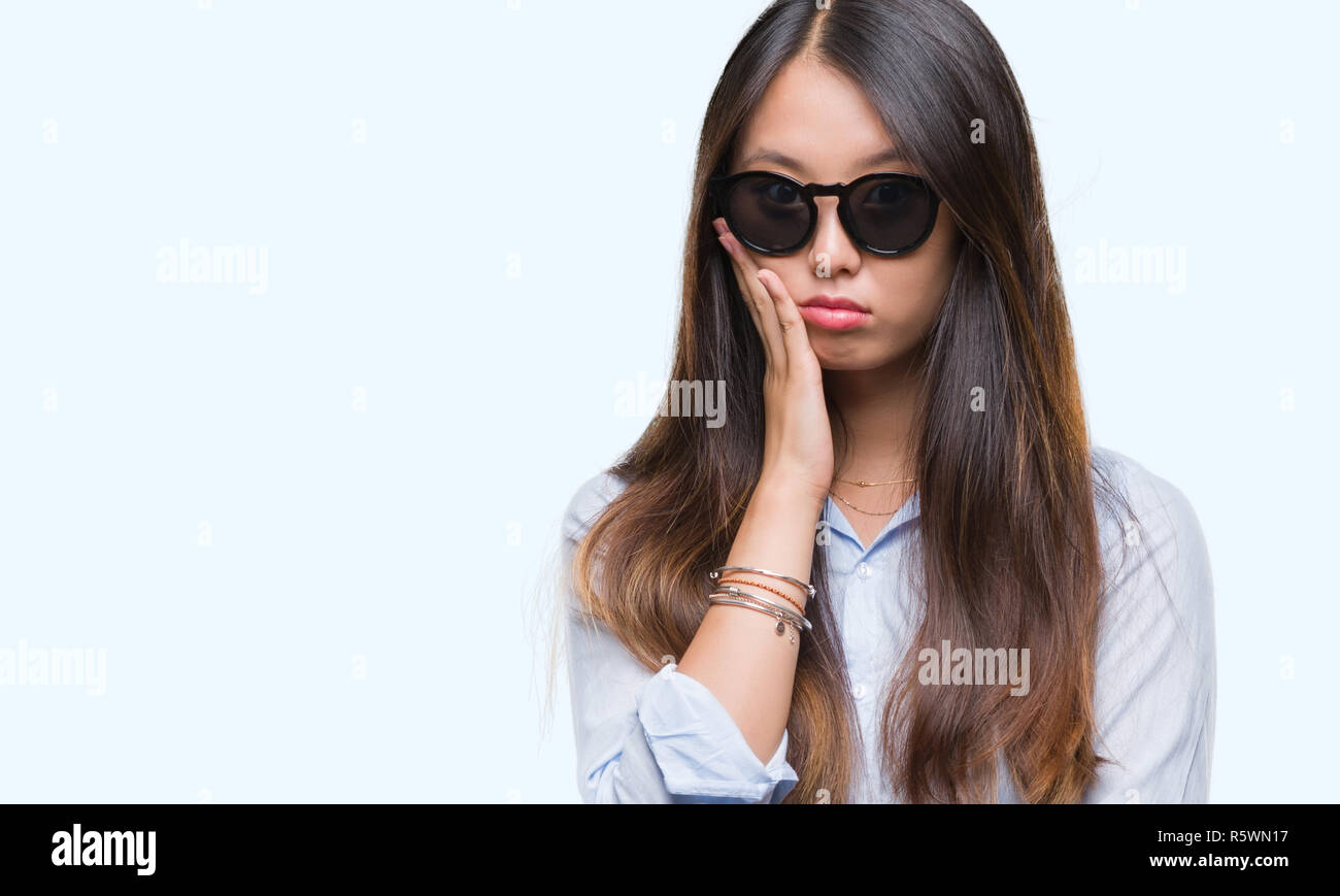 Young asian woman wearing sunglasses over isolated background thinking