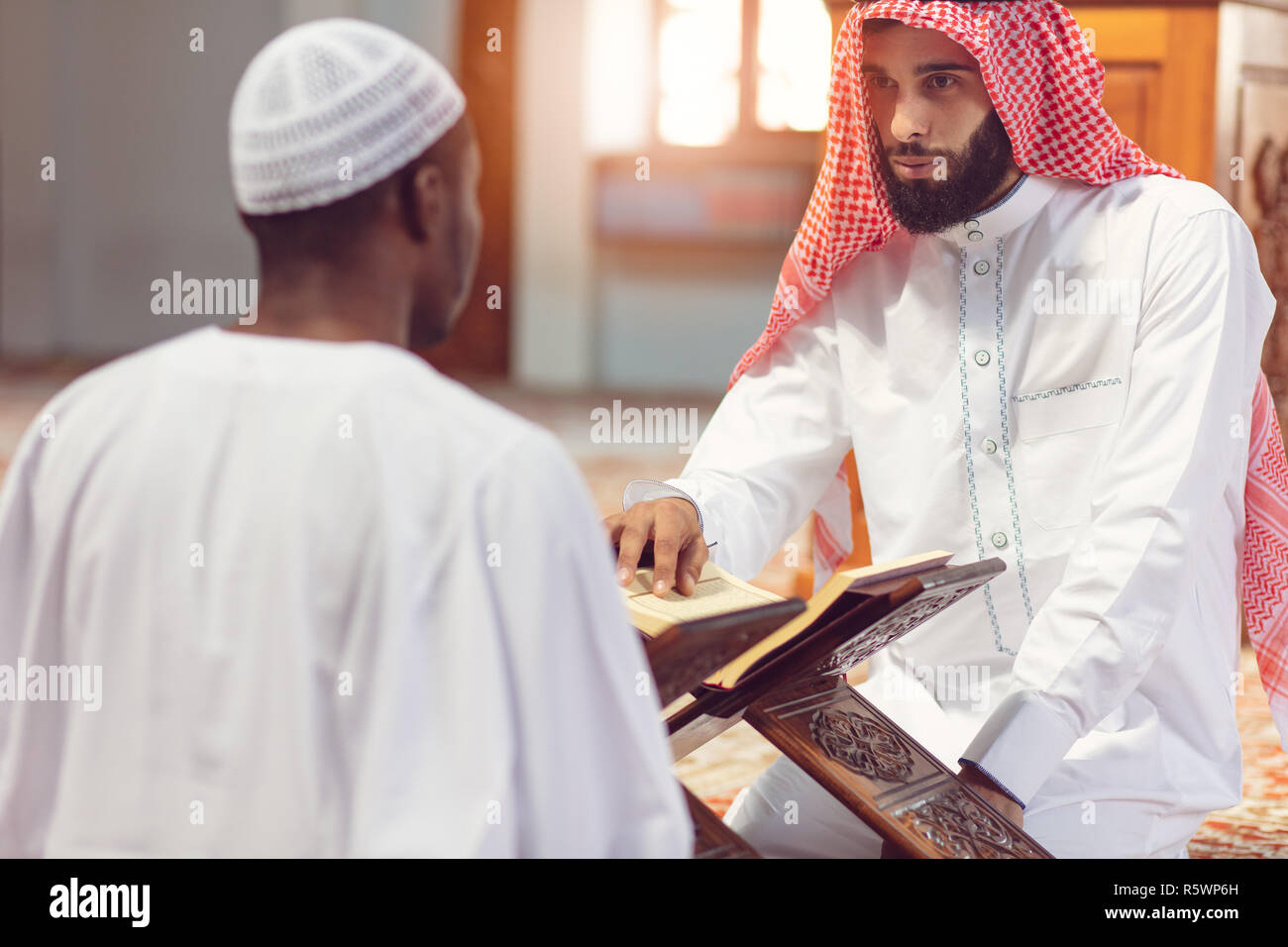 Muslim men praying with holy books in mosque Stock Photo