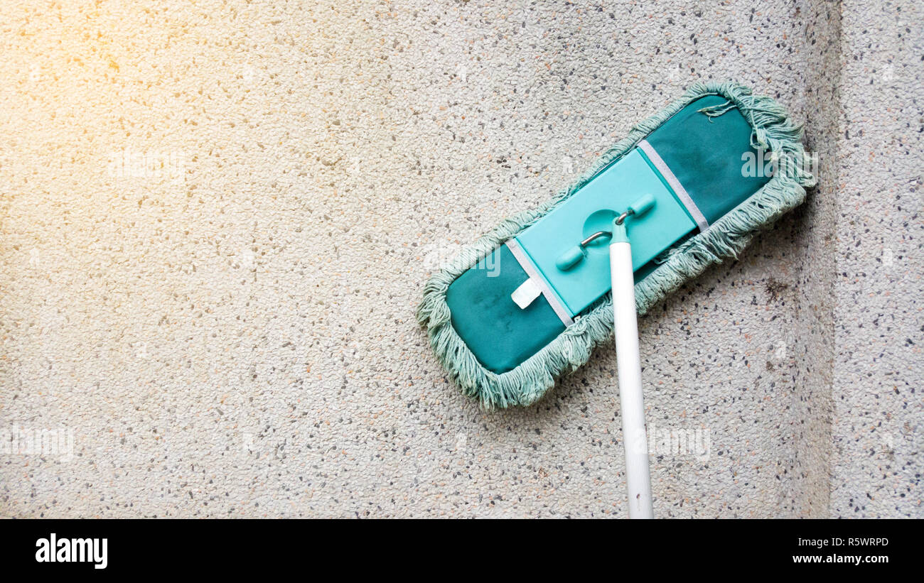 A green dirty mob or swab lean on dirty concrete wall. The floor mop is  used to clean the floor clean. Cleaning and exercise by housework concept  Stock Photo - Alamy