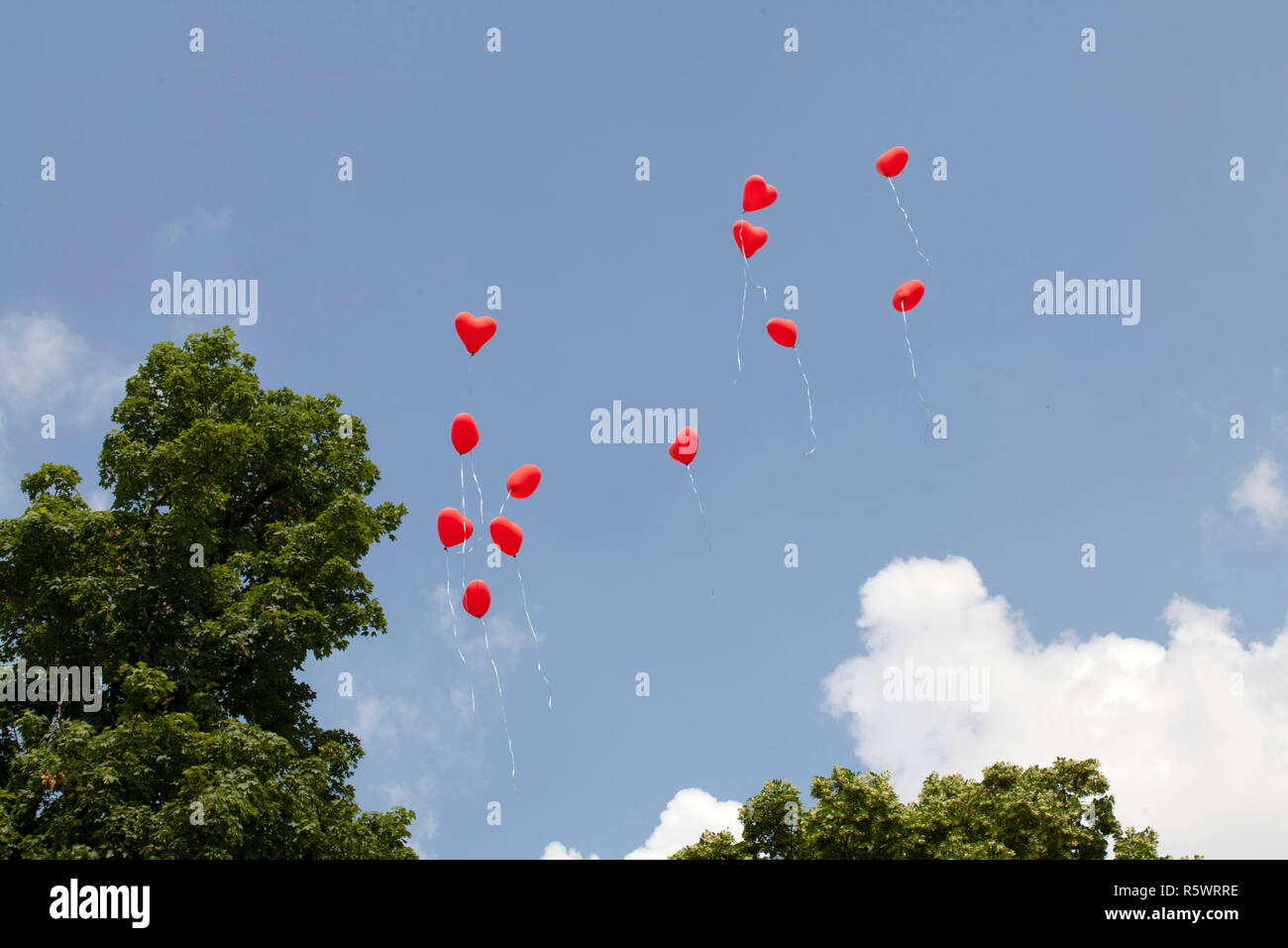 Red heart balloons fly in blue sky Stock Photo - Alamy