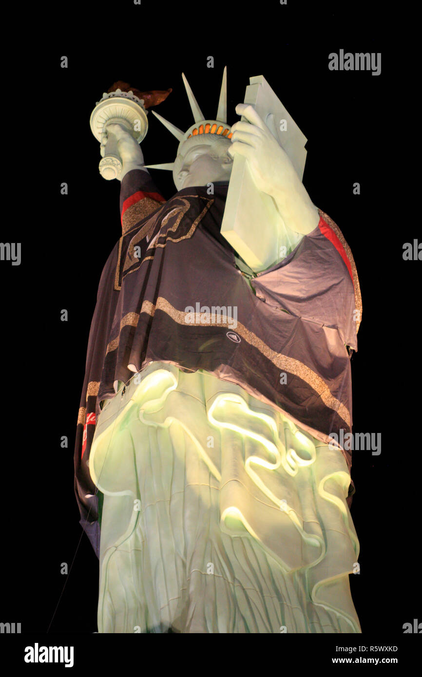 Statue of Liberty wearing a Golden Knights jersey lit up at night in