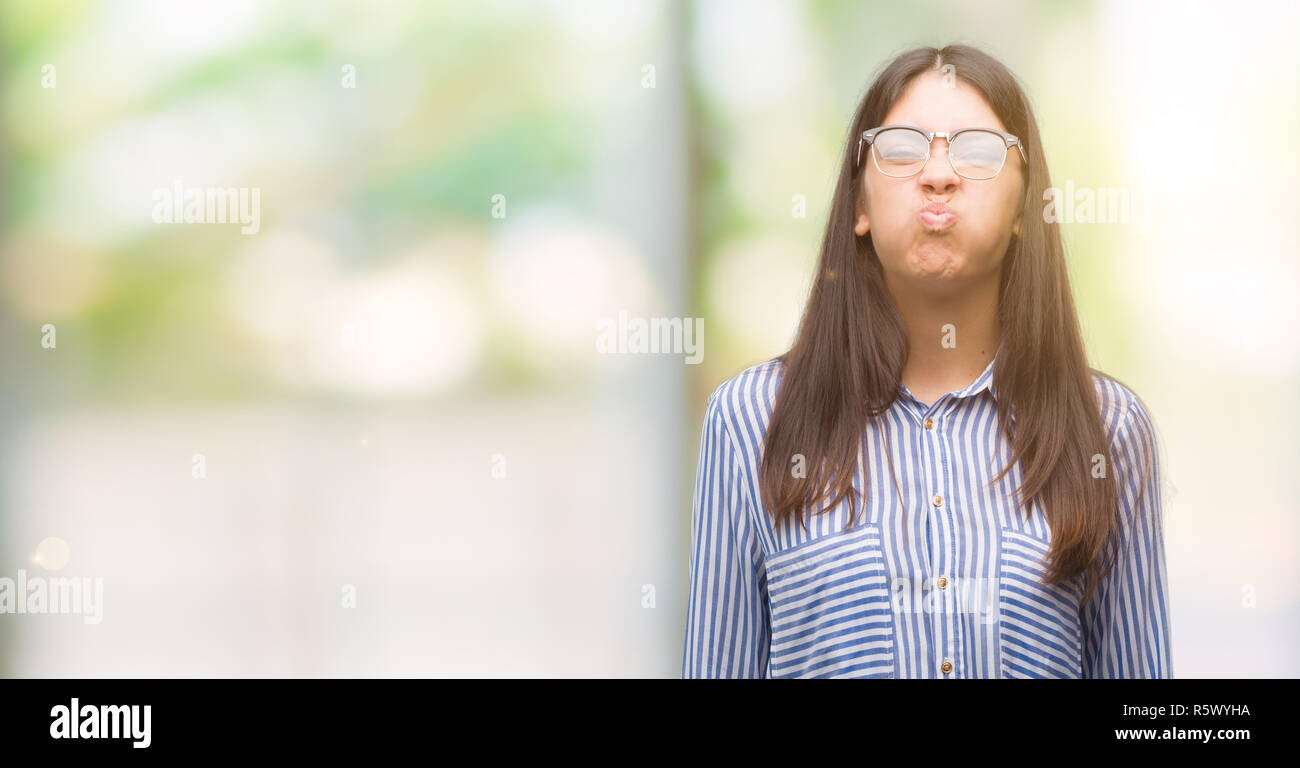 Puffing Cheeks Young beautiful hispanic business woman puffing cheeks with funny face ...