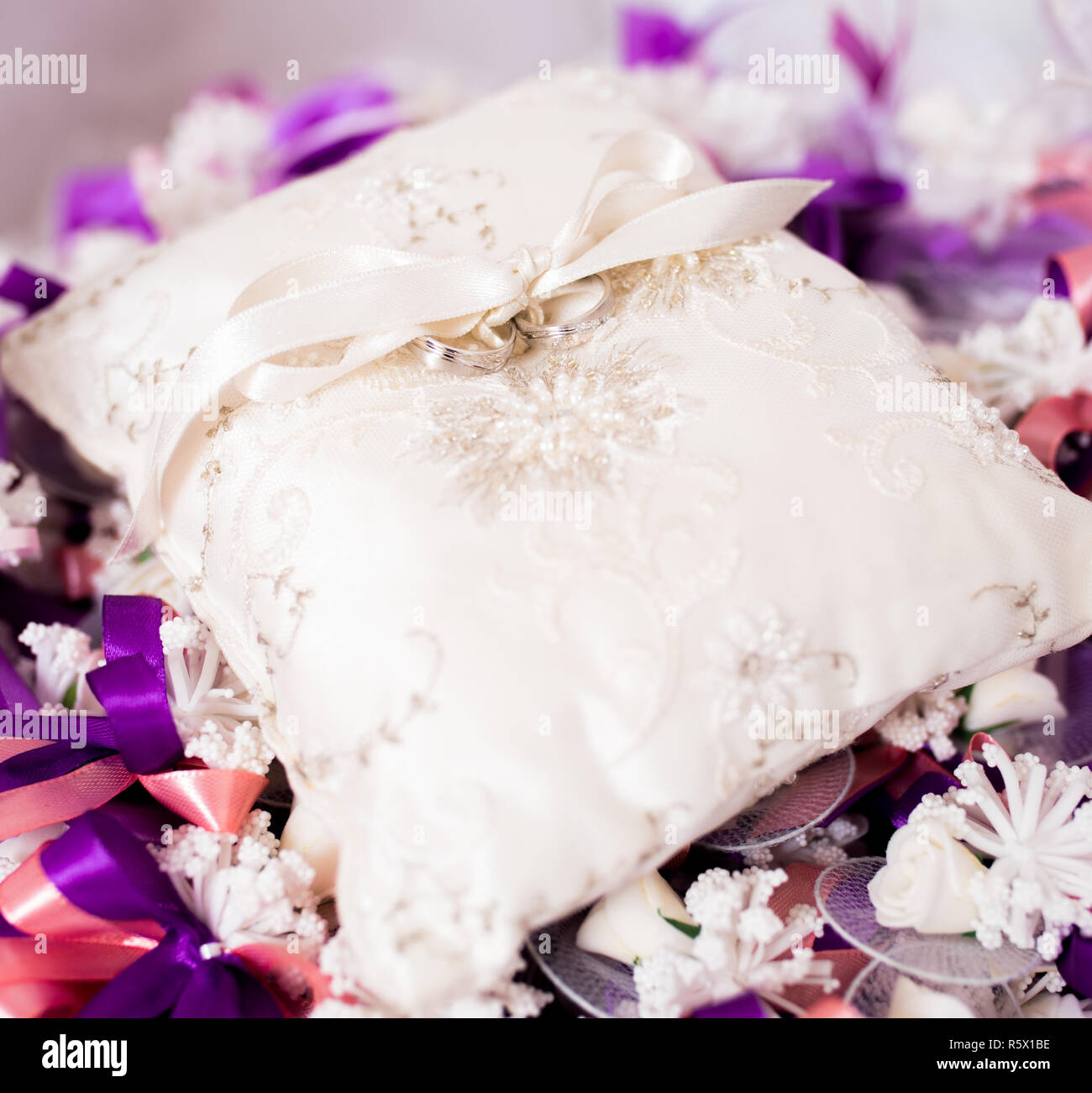 Wedding ring on a decorative cushion with purple decorative ribbons. Stock Photo