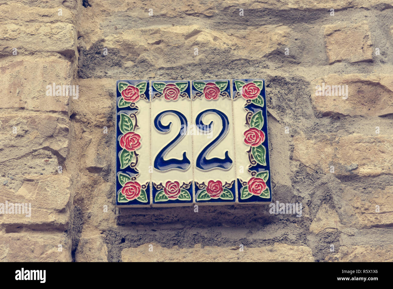 House number written on ceramic plate and placed on building Stock