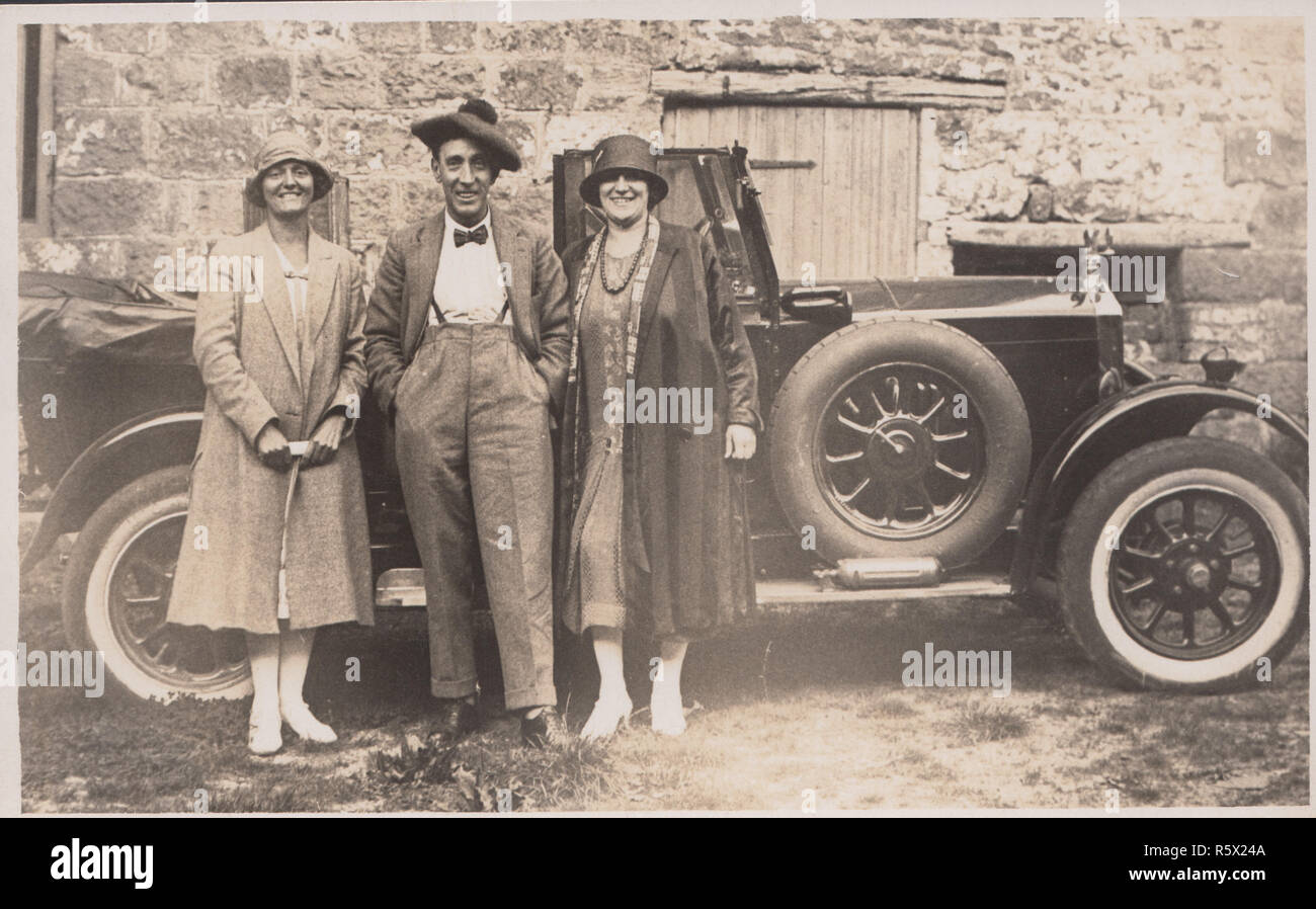 Vintage 1920's - 1930's Photographic Postcard of Two Fashionable Women and a Fashionable Man Standing in Front of an Open Top Car Stock Photo