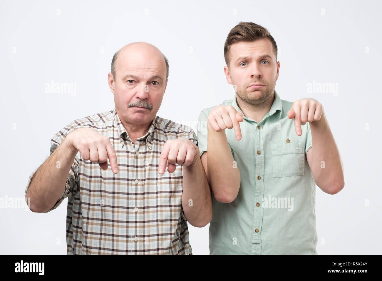 Two mature men being sad and pointing down. Stock Photo