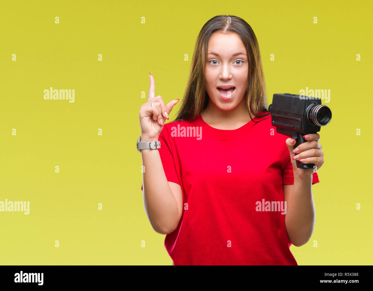 Young beautiful caucasian woman filming using vintage video camera over isolated background surprised with an idea or question pointing finger with ha Stock Photo