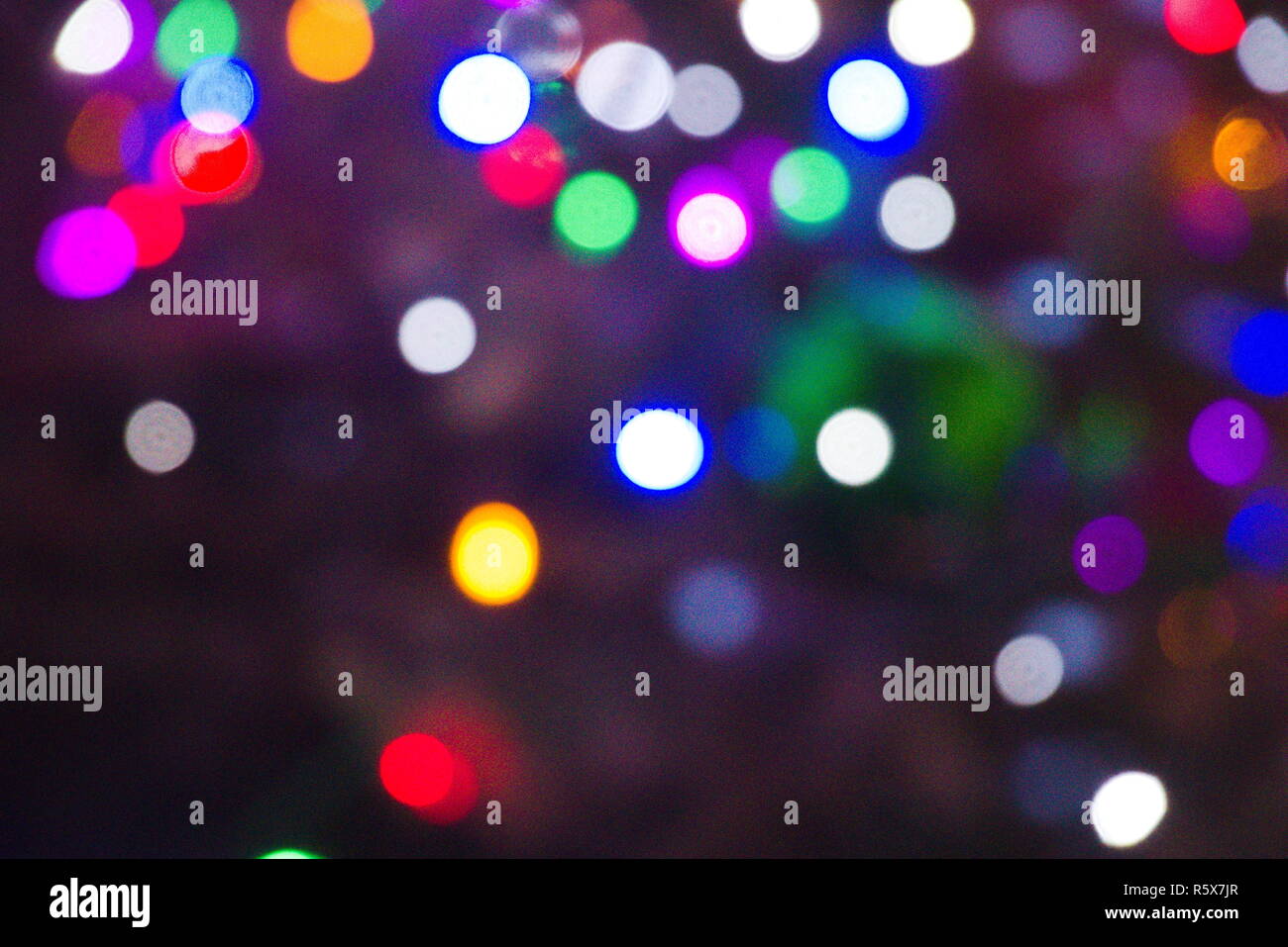 Red, green, blue, white, green, purple and orange bokeh on a blue/black night sky. Christmas lights that are out of focus. Stock Photo