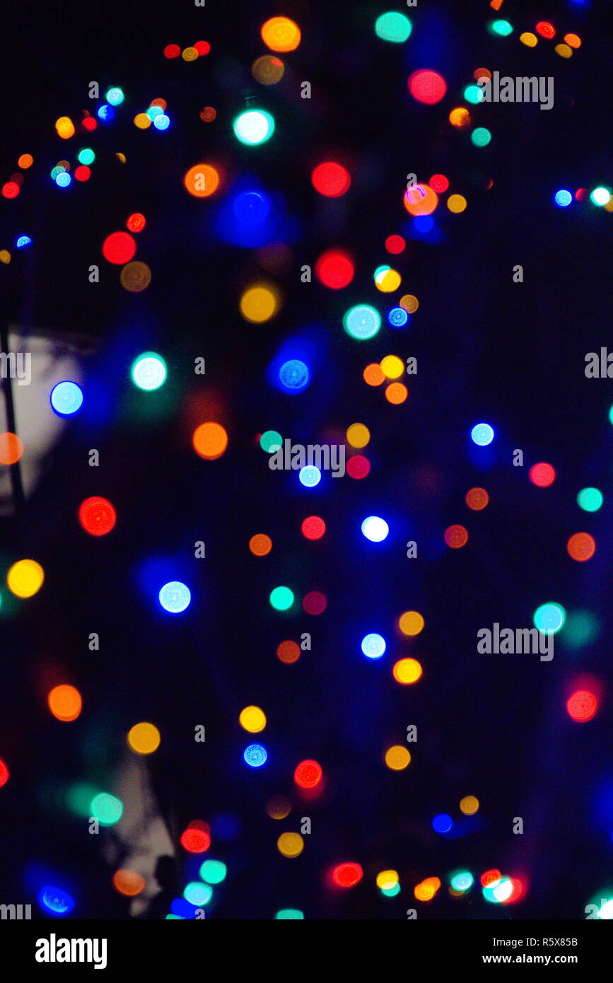 Red, green, blue, white, green, purple and orange bokeh on a blue/black night sky. Christmas lights that are out of focus. Stock Photo