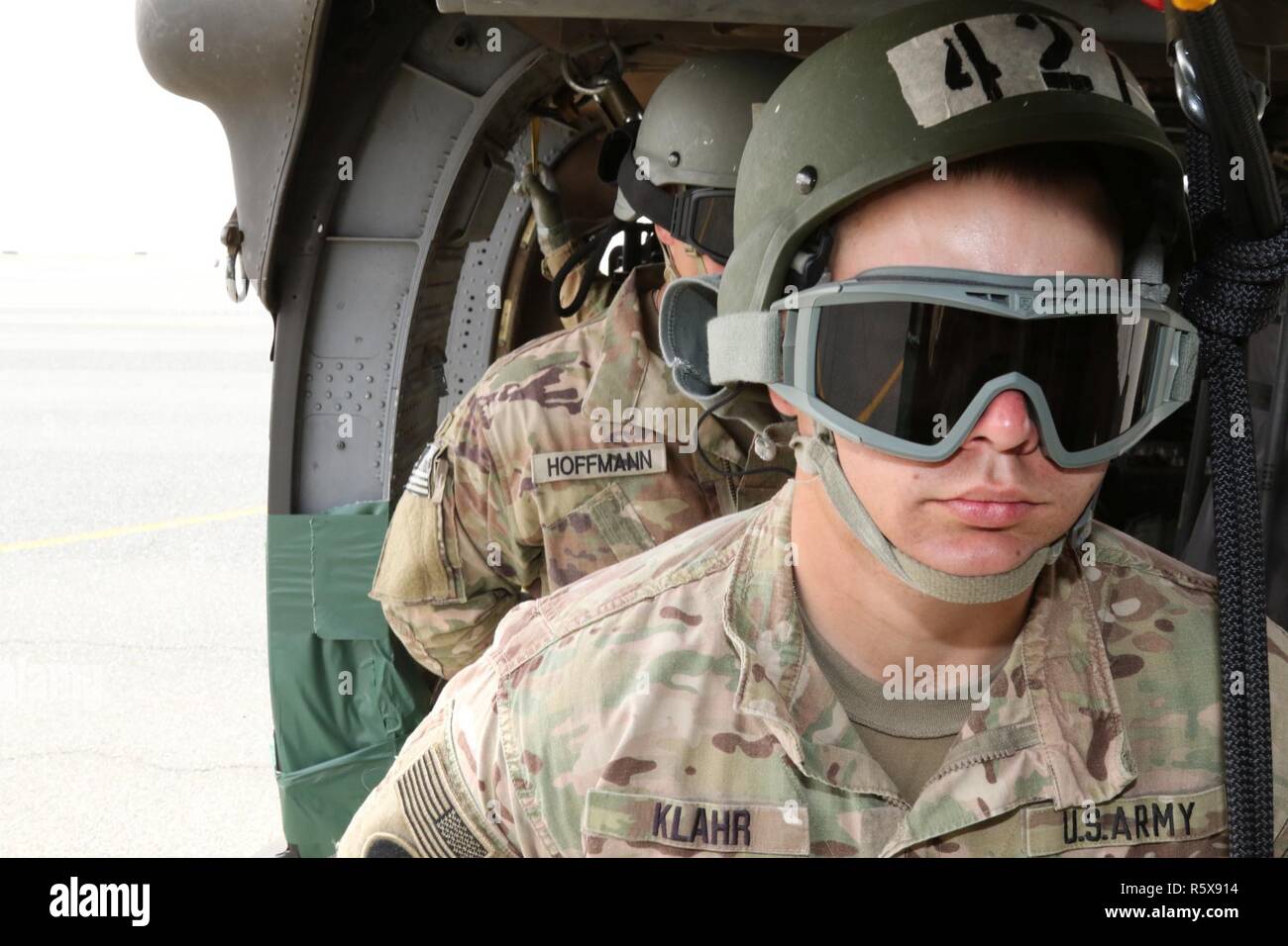 U.S. Army Spc. Steven Klahr (front), air traffic controller, 77th Combat Aviation Brigade, and Spc. Jacob Hoffman (rear), multiple launch rocket system crewmember, 169th Field Artillery Brigade, listen to instructions before they rappel out of a UH-60 Black Hawk helicopter, during day nine of U.S. Army Central’s first Air Assault Course, April 13, 2017, at Camp Buehring, Kuwait. The Air Assault Course allows U.S. military personnel in the U.S. Army Central area of operations the unique opportunity to become air assault qualified, while deployed outside the continental United States. Stock Photo