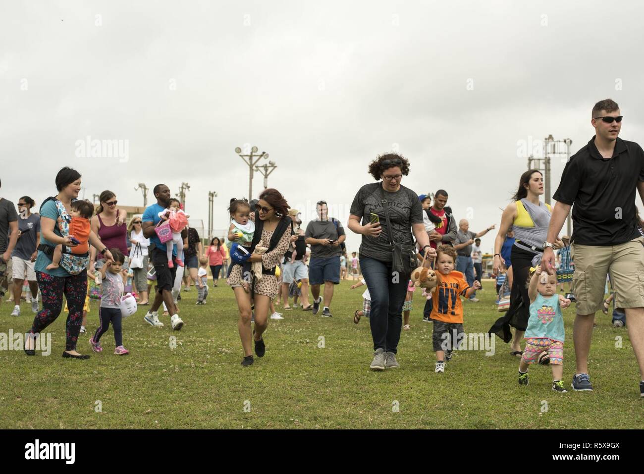 Families race to collect Easter eggs scattered on the Four Diamonds softball field April 15, 2017, at Kadena Air Base, Japan. The Eggsplosion, an annual event hosted by the 18th Force Support Squadron, featured egg hunts for different age groups and also hosted a “Kiddie Land” area with amusement rides designed for children. Stock Photo