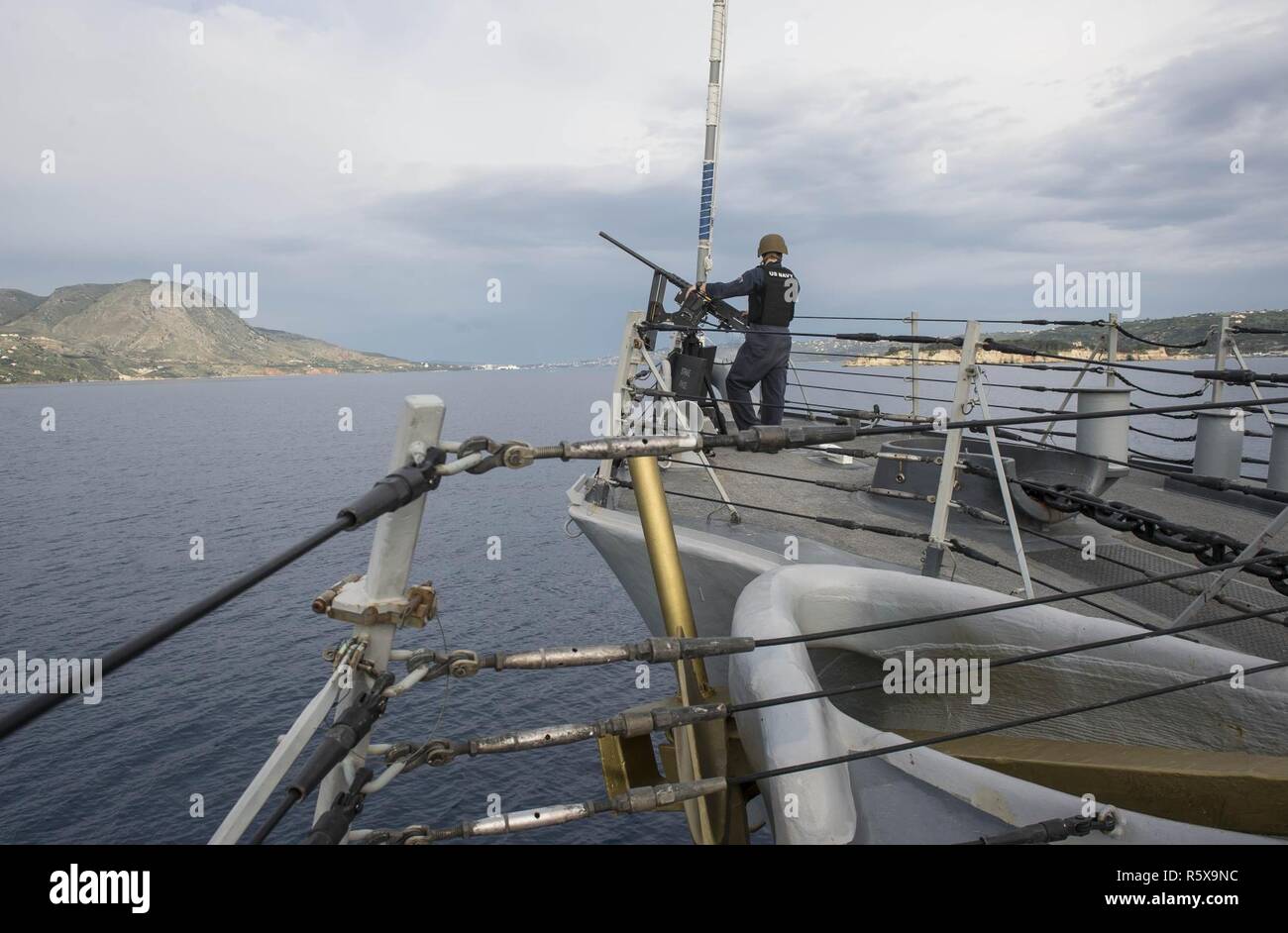 SOUDA BAY, Greece (April 17, 2017) Information Systems Technician 3rd Class Ryan Guerra, from Philadelphia, mans a .50-caliber machine gun aboard USS Ross (DDG 71) as the ship arrives in Souda Bay, Greece for a scheduled port- visit April 17, 2017. USS Ross, an Arleigh Burke-class guided-missile destroyer, forward-deployed to Rota, Spain, is conducting naval operations in the U.S. 6th Fleet area of operations in support of U.S. national security interests in Europe and Africa. Stock Photo