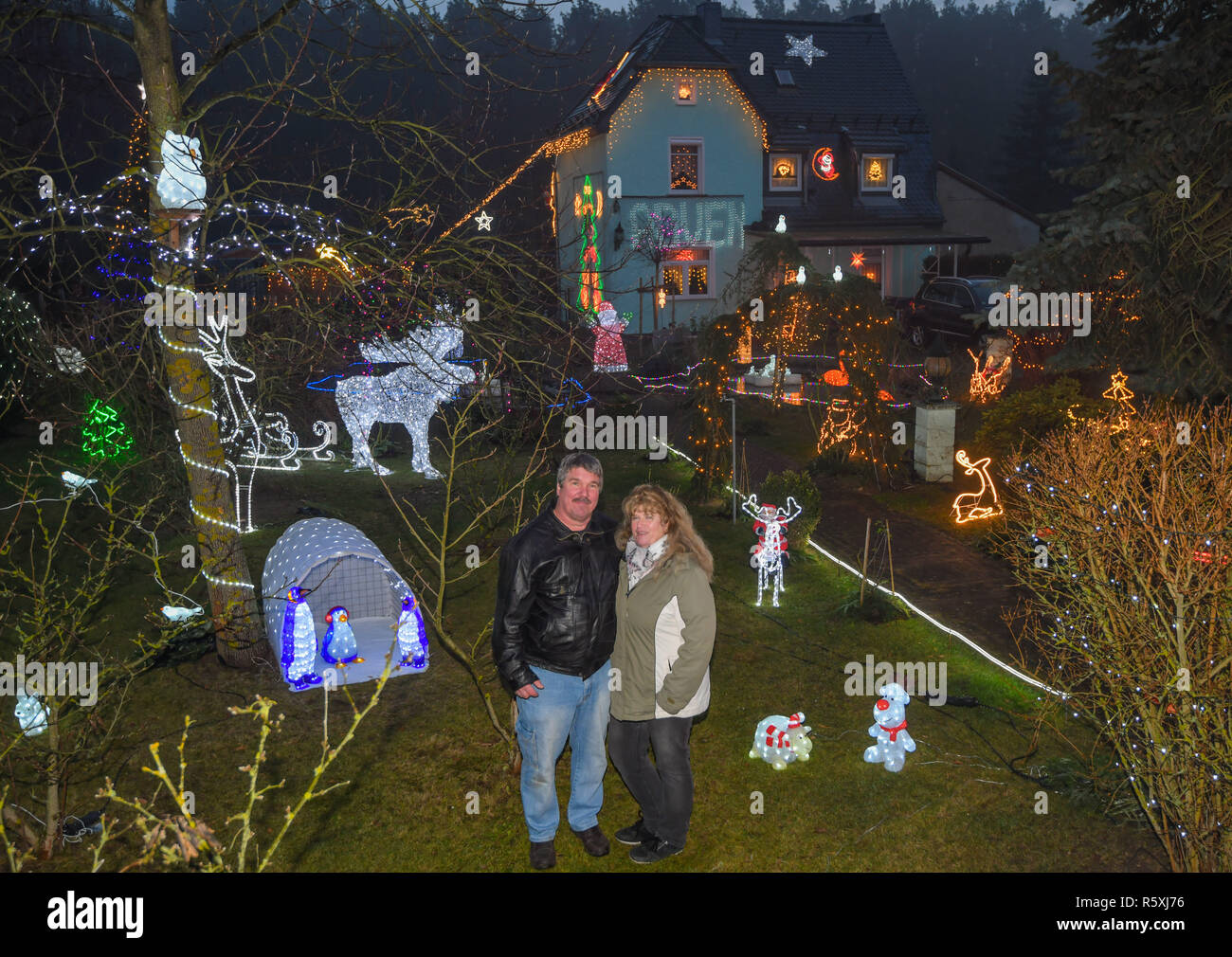 01 December 2018, Brandenburg, Berkenbrück: Gabriele and Harald Muschner  stand in their Christmas-lit garden. Fairy lights, glowing stars and  decorated Christmas trees are for many people part of the pre-Christmas  season. But