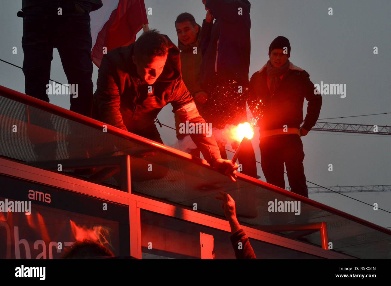 A man hands over a flare on top of a bus stop, Polish National Independence Day march, 100 year anniversary, Warsaw, 11 November 2018, Poland, 2018 Stock Photo