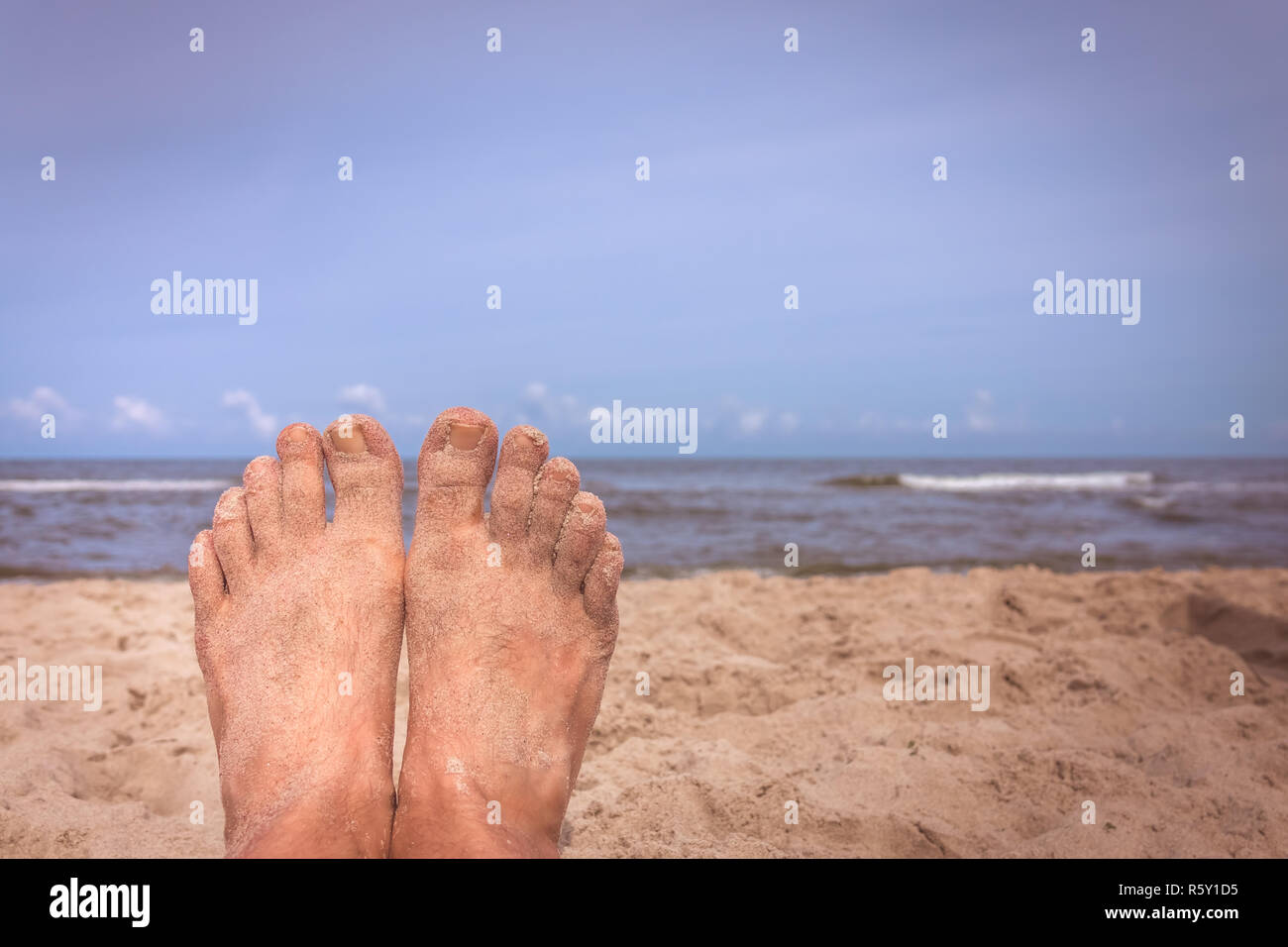 Mans feet on the beach Stock Photo
